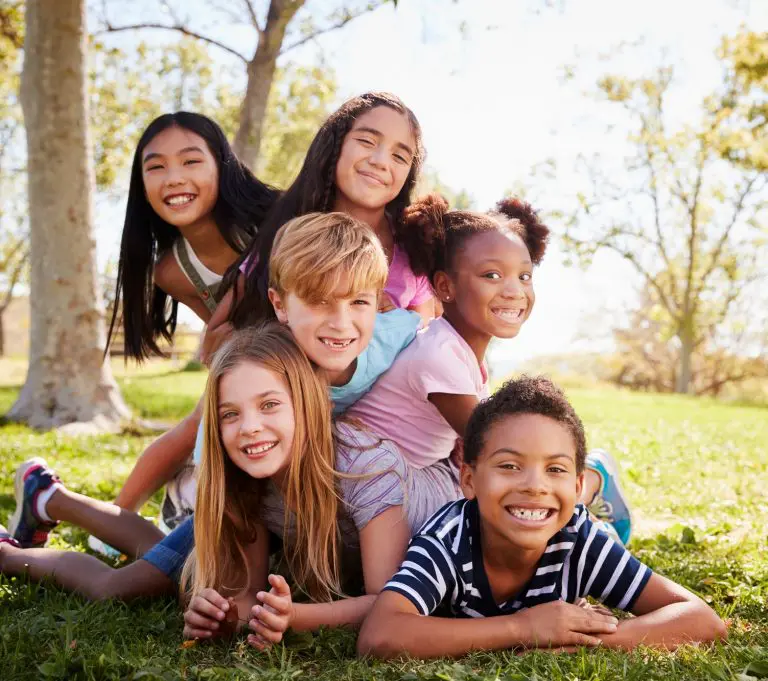Multi-ethnic group of kids lying on each other in a park